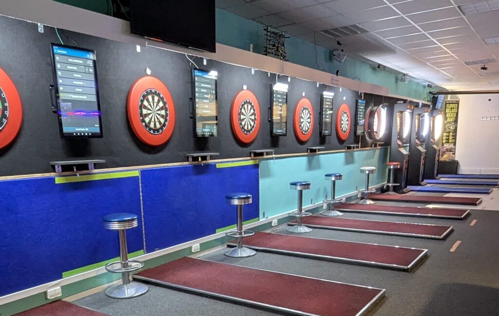 Ein leerer Dartsraum mit mehreren Dartscheiben und rot umrahmten Spielzielen an der Wand.