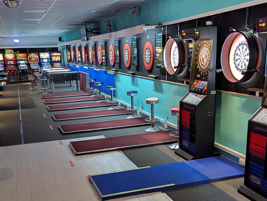 Mehrere elektronische Dartscheiben in einer Spielhalle mit bunten Lichtern.