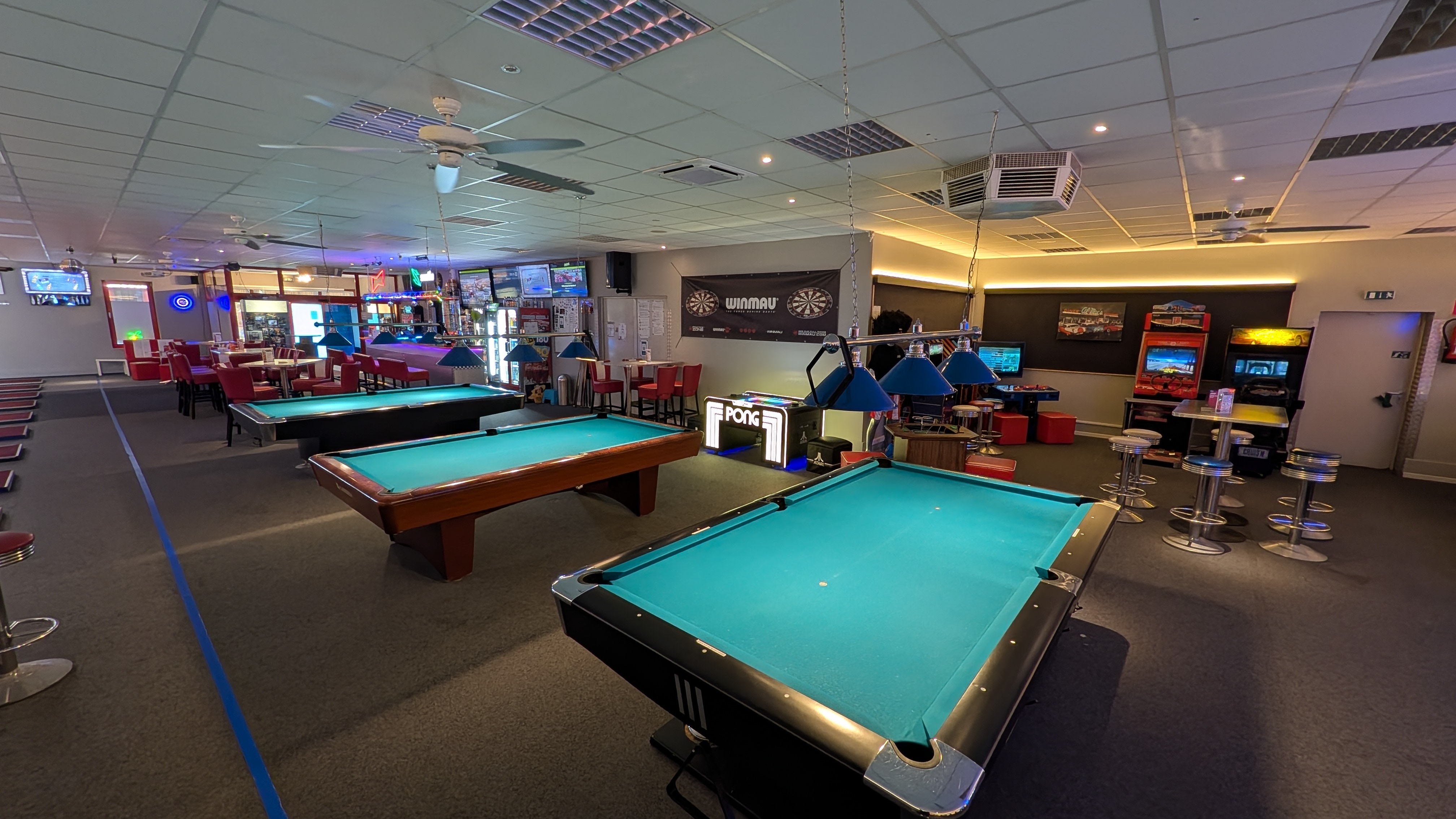 Spielhalle mit mehreren Billardtischen Dartscheiben und Arcade Automaten
