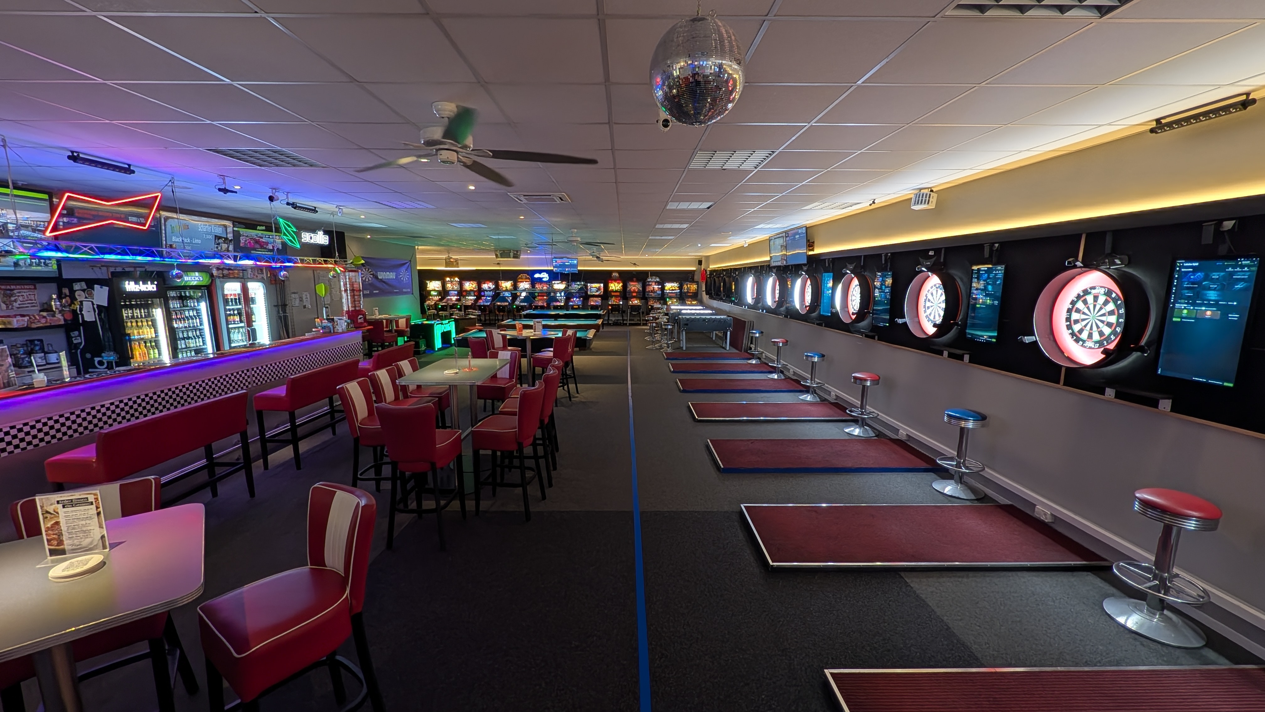 Dartbar im Retro Stil mit roten Sitzen Dartscheiben und Discokugel