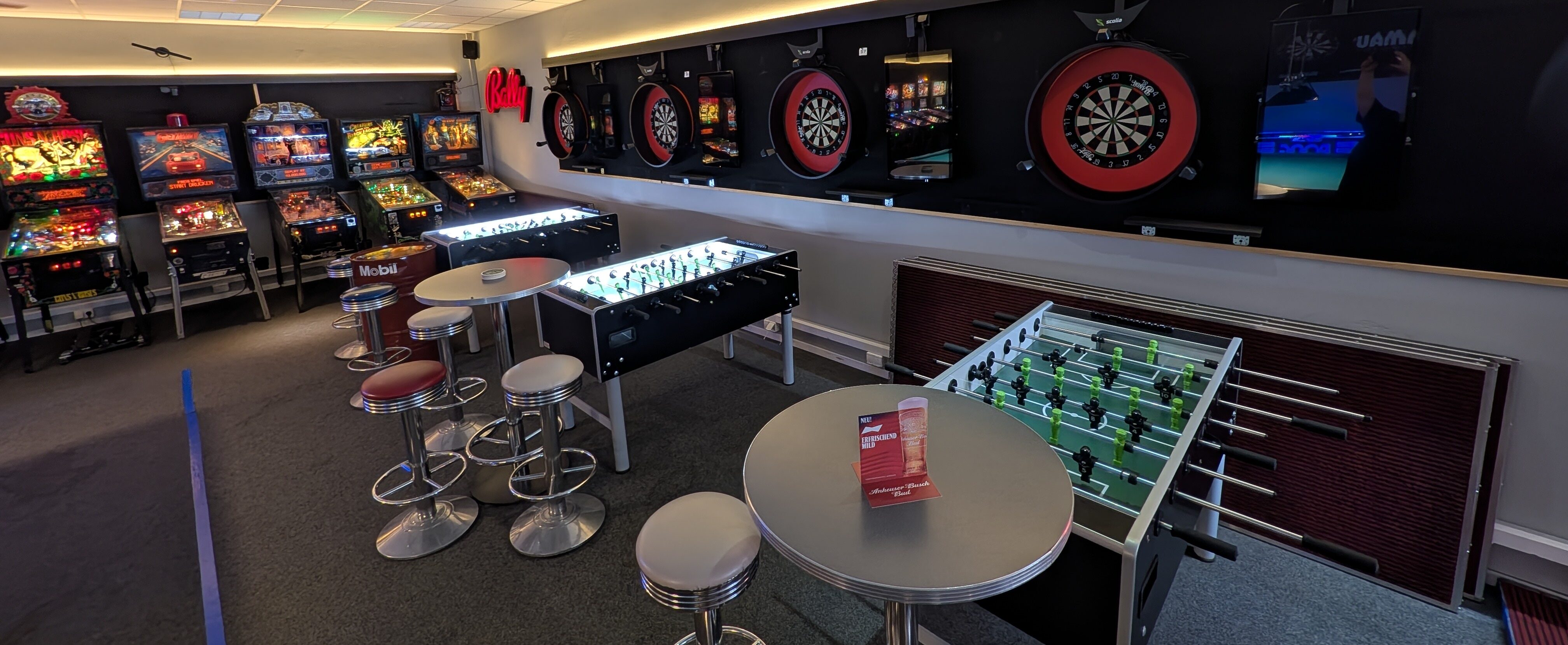 Spielhalle mit Flipperautomaten Dartscheiben und Tischkicker in warmem Licht
